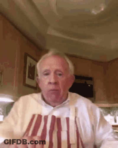 Elderly Man Sitting At Table In Apron GIF