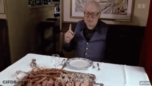 Elderly Man Sitting At Table With Food And Meat Tray GIF