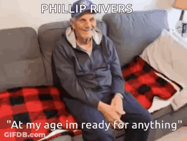 Elderly Man Sitting On Couch With Plaid Blanket And Hat GIF