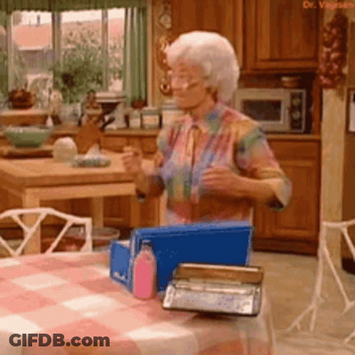 Elderly Woman At Table With Blue Box In Kitchen GIF