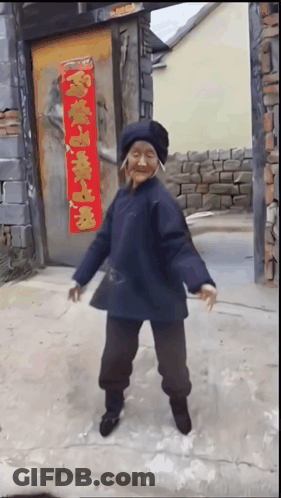 Elderly Woman Dancing In Front Of Door With Chinese Characters GIF
