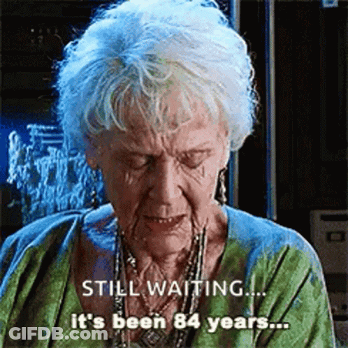 Elderly Woman Gray Hair Green Shirt Says Still Waiting It's Been 84 Years GIF