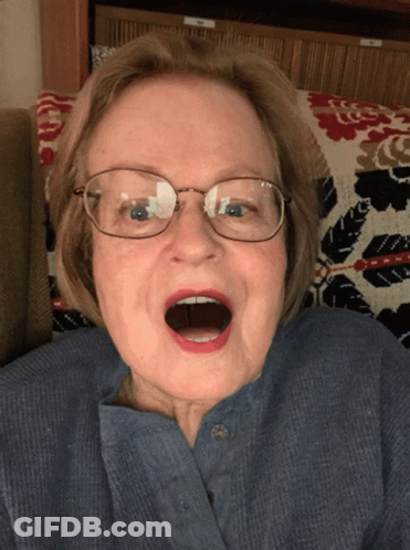 Elderly Woman In Blue Shirt And Glasses Open Mouth GIF
