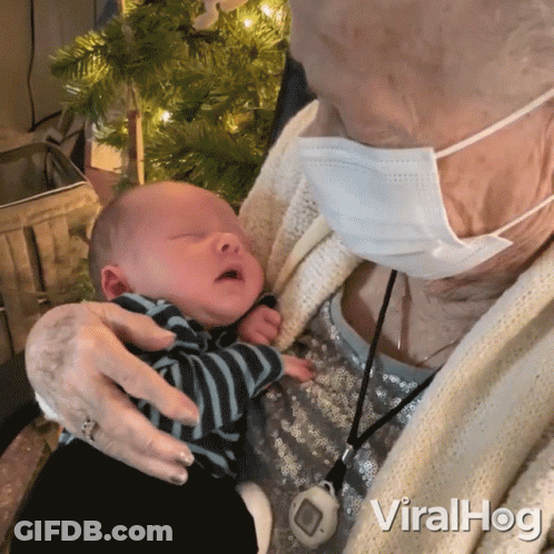 Elderly Woman In Face Mask Holding Baby GIF