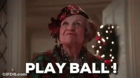 Elderly Woman In Hallway With Christmas Tree Says Play Ball GIF