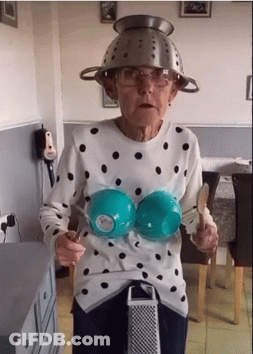 Elderly Woman In Polka Dot Shirt With Strainer On Head GIF