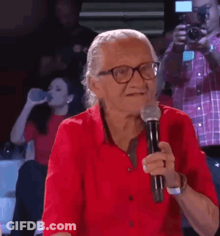 Elderly Woman In Red Shirt Holding Microphone GIF