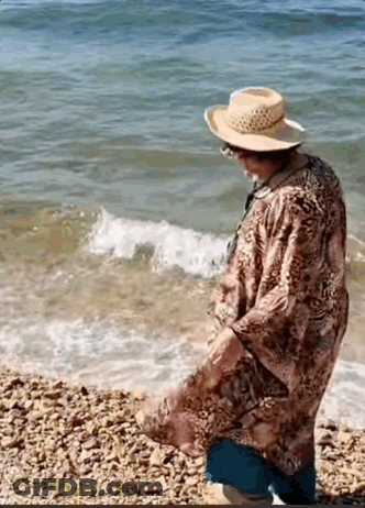 Elderly Woman In Straw Hat On Rocky Beach GIF