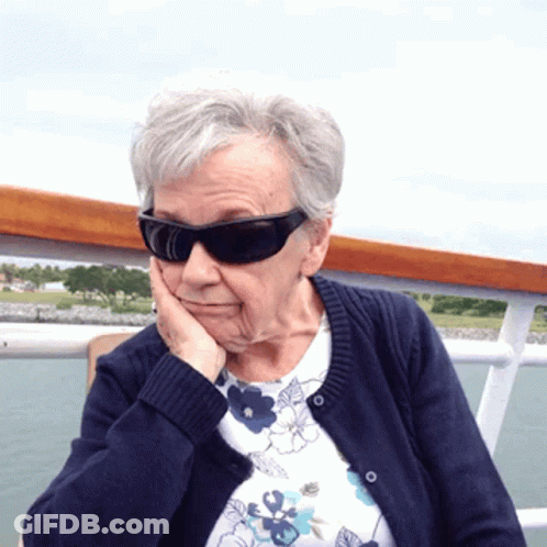 Elderly Woman In Sunglasses And Blue Sweater Touching Face GIF