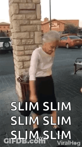Elderly Woman Standing Next To Brick Wall GIF