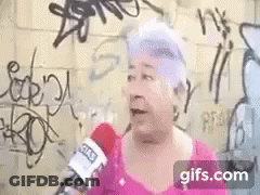 Elderly Woman Talking Into Microphone In Front Of Graffiti Wall GIF