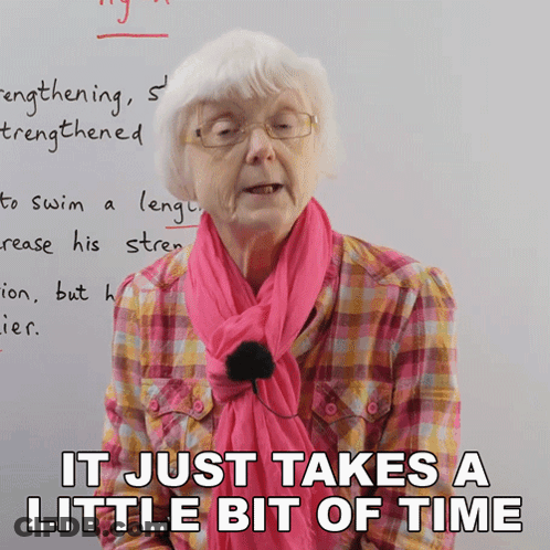 Elderly Woman With Glasses And Pink Scarf Saying It Just Takes A Little Bit Of Time GIF