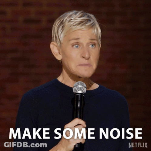 Ellen Degeneres Holds A Microphone In Front Of A Brick Wall And Says Make Some Noise GIF