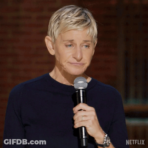 Ellen Degeneres Is Holding A Microphone In Front Of A Brick Wall With Netflix Written On The Bottom Right GIF