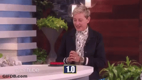 Ellen Degeneres Is Sitting At A Table With A Button That Says 1.0 On It GIF