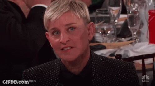 Ellen Degeneres Is Sitting At A Table With Wine Glasses And Making A Funny Face . GIF