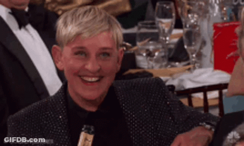 Ellen Degeneres Is Smiling While Sitting At A Table GIF