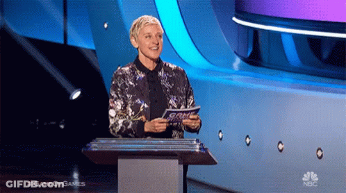 Ellen Degeneres Stands At A Podium Holding A Piece Of Paper That Says Game Of Games On The Bottom GIF