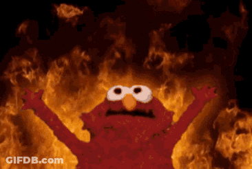 Elmo From Sesame Street Is Standing In Front Of A Fire GIF