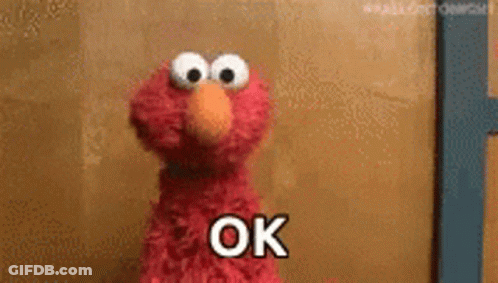 Elmo From Sesame Street Is Standing In Front Of A Wall And Says Ok . GIF