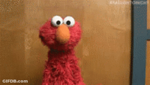 Elmo From Sesame Street Is Standing In Front Of A Wall . GIF