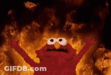 Elmo From Sesame Street Is Standing In Front Of A Wall Of Fire . GIF