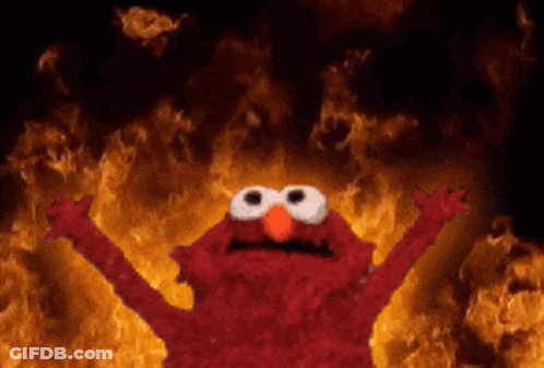 Elmo From Sesame Street Is Standing In Front Of A Wall Of Fire GIF