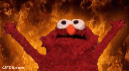 Elmo From Sesame Street Is Standing In Front Of A Wall Of Fire . GIF