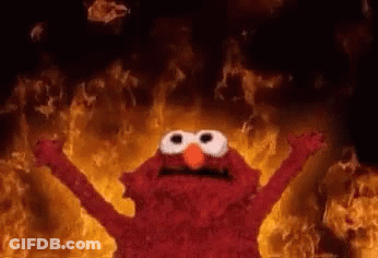 Elmo From Sesame Street Is Standing In Front Of A Wall Of Flames . GIF