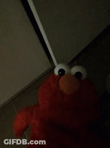 Elmo From Sesame Street Is Standing In The Corner Of A Dark Room GIF