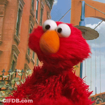 Elmo From Sesame Street Is Standing On A City Street GIF