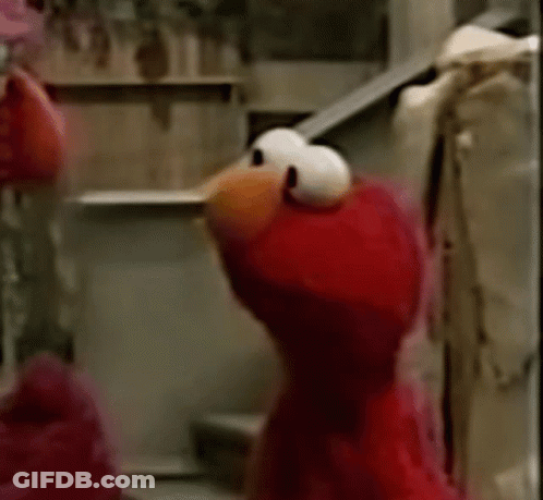 Elmo From Sesame Street Is Standing On A Set Of Stairs And Looking At The Camera . GIF