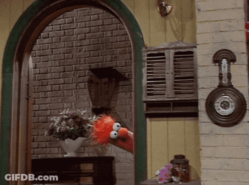 Elmo From Sesame Street Looks Out A Window With A Vase Of Flowers GIF