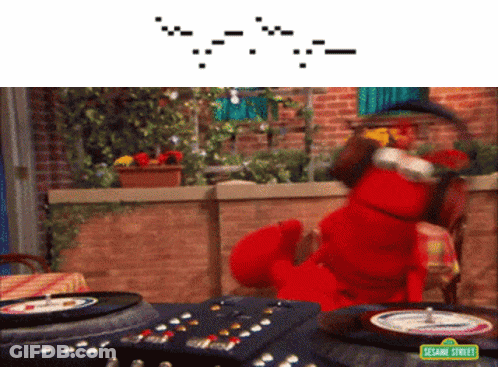 Elmo From Sesame Street Sits At A Table With A Remote Control GIF