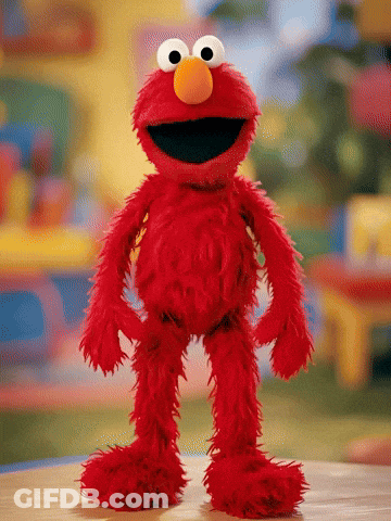 Elmo From Sesame Street Stands On A Wooden Table GIF