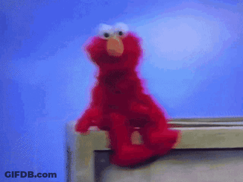 Elmo The Sesame Street Character Is Sitting On A Shelf GIF
