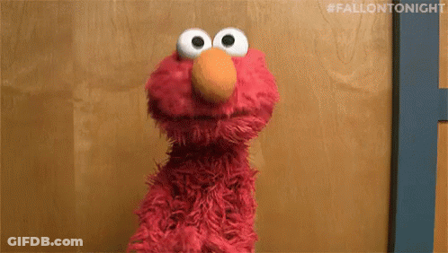 Elmo The Sesame Street Character Is Standing In Front Of A Wooden Wall . GIF