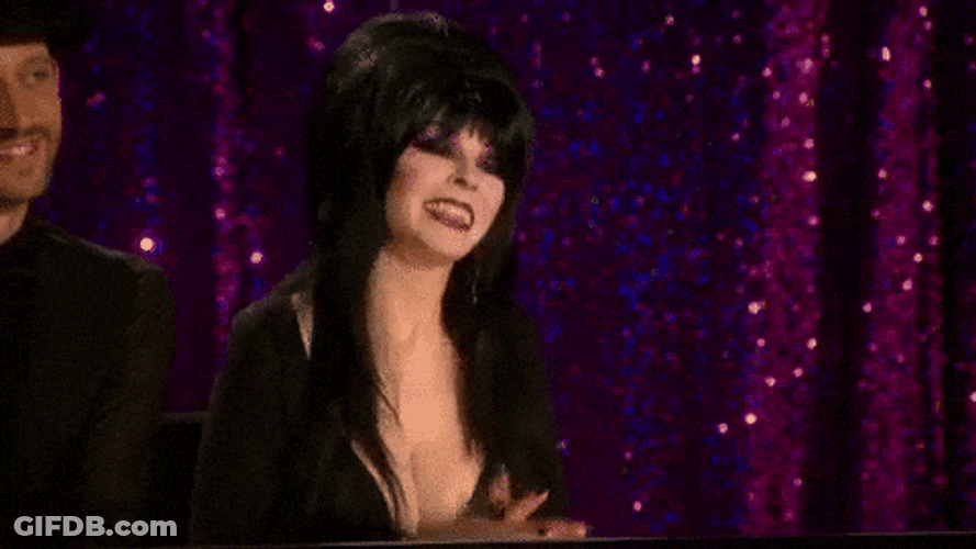 Elvira Smiling While Touching Her Chest GIF