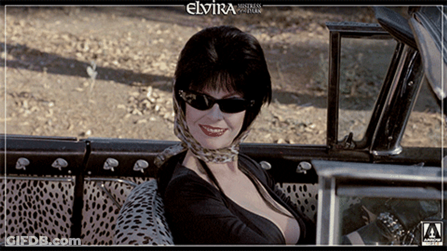 Elvira Waving Hello From Her Car GIF