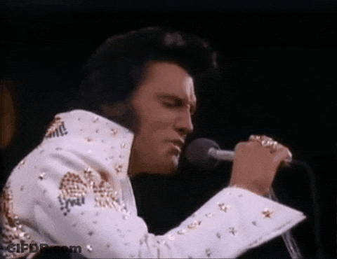 Elvis Presley Is Singing Into A Microphone While Wearing A White And Gold Suit . GIF
