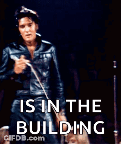 Elvis Presley Singing Into A Microphone With The Words " Is In The Building " Behind Him GIF