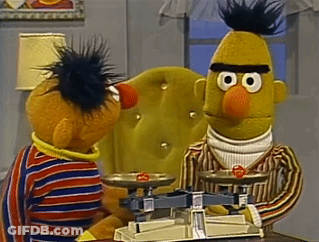 Ernie And Bert From Sesame Street Are Sitting At A Table With A Scale GIF
