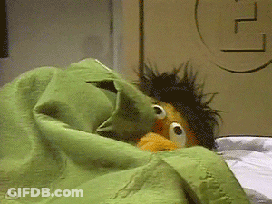 Ernie From Sesame Street Is Laying In Bed With A Green Blanket GIF