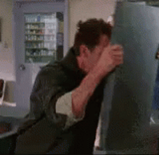 Exasperated Man Bangs Head Against Wall GIF