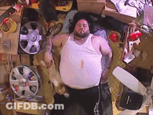 Fat Man Laying On Bed Surrounded By Wheels And Boxes GIF