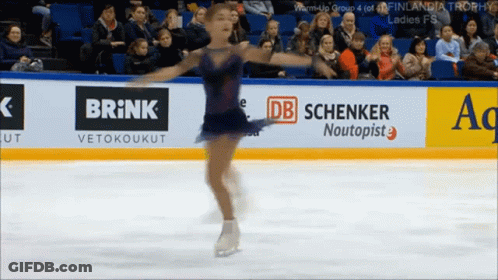 Female Figure Skater Performing In Front Of Brick Banner GIF