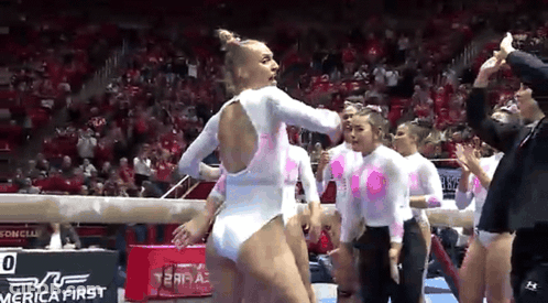 Female Gymnasts On Balance Beam In Front Of Crowd GIF
