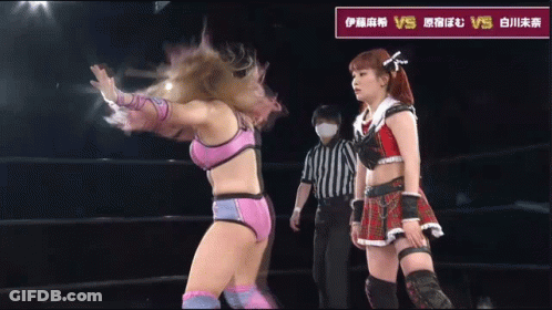 Female Wrestler Next To Wrestler In Red Pants With X On Pocket GIF