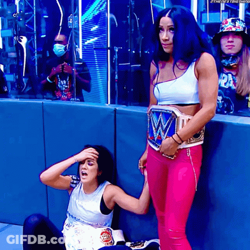 Female Wrestler Standing Beside Sitting Wrestler GIF