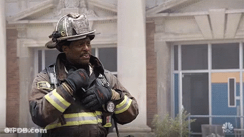 Firefighter Standing In Front Of Building With Gloves And Helmet GIF